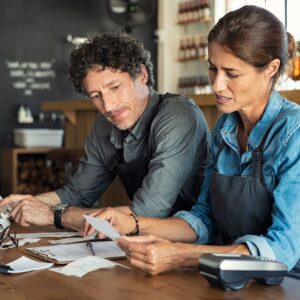 two chefs looking at paperwork and using a calculator