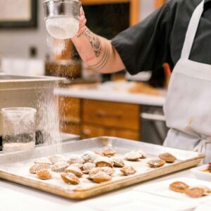 a person dusting pastries with powdered sugar